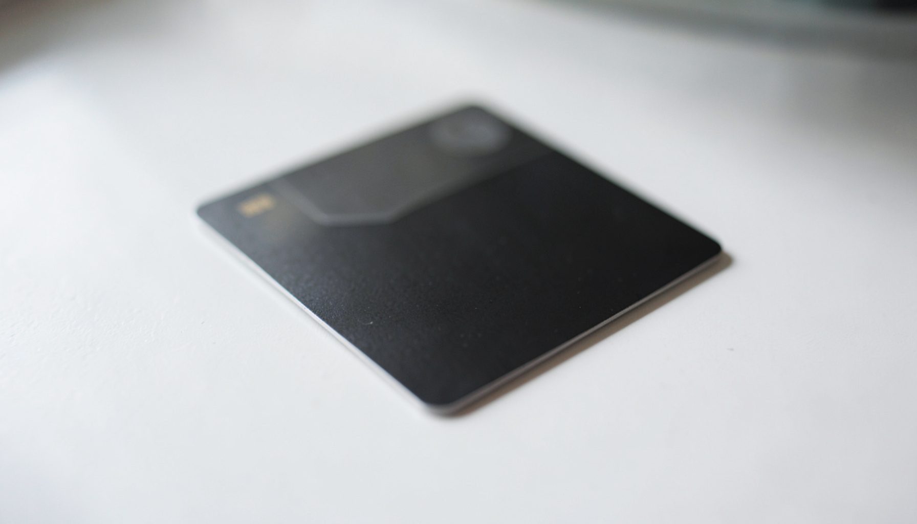 A close-up of a dark prepaid card resting on a clean white desk surface, soft natural light casting gentle shadows, professional and understated mood.