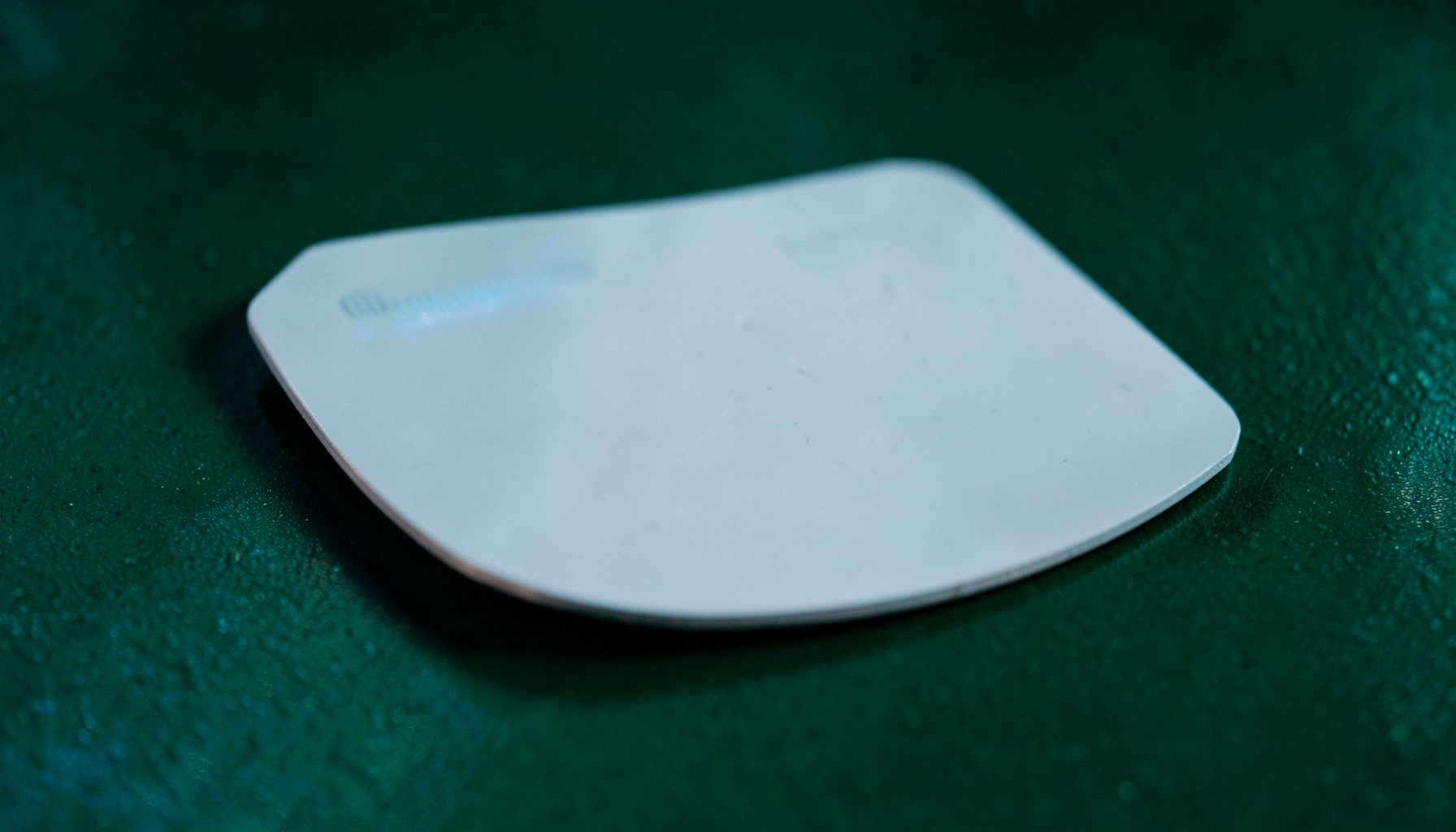 Close-up of a plain prepaid debit card resting on a dark green surface with muted blue-green light reflections